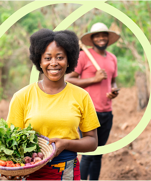 A woman in the countryside with a basket full of fresh vegetables.
