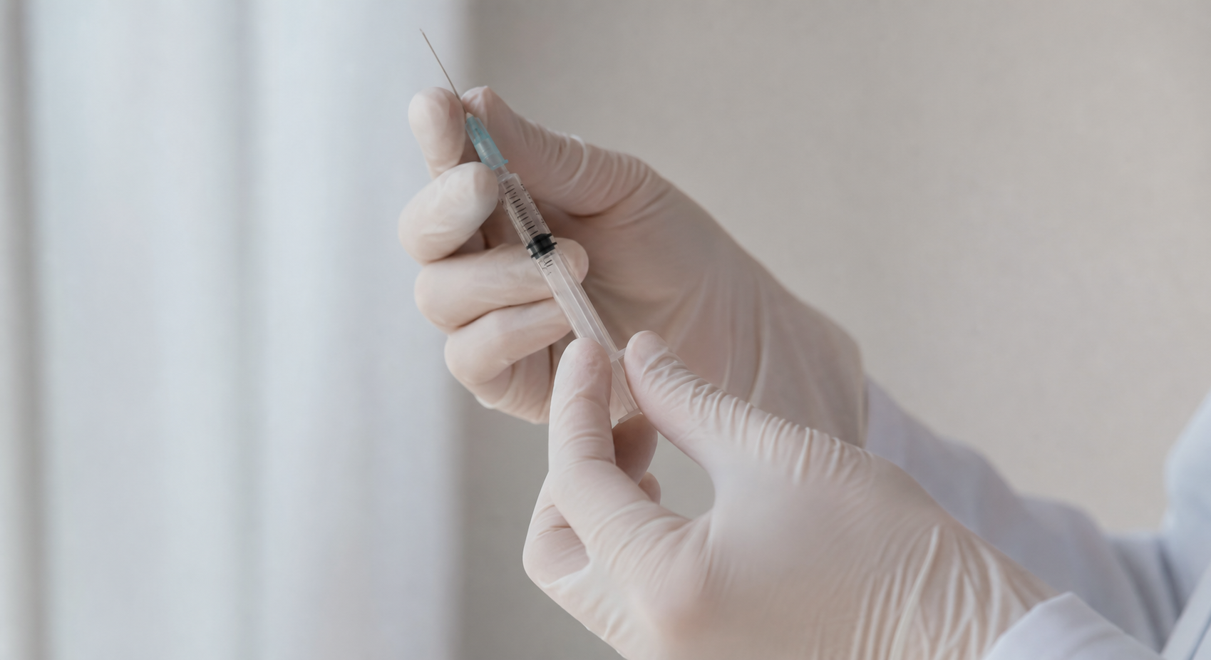 A close-up of a medical professional's gloved hands preparing a small syringe in a clean clinical setting, soft natural light, calm and professional atmosphere, no text or labels anywhere