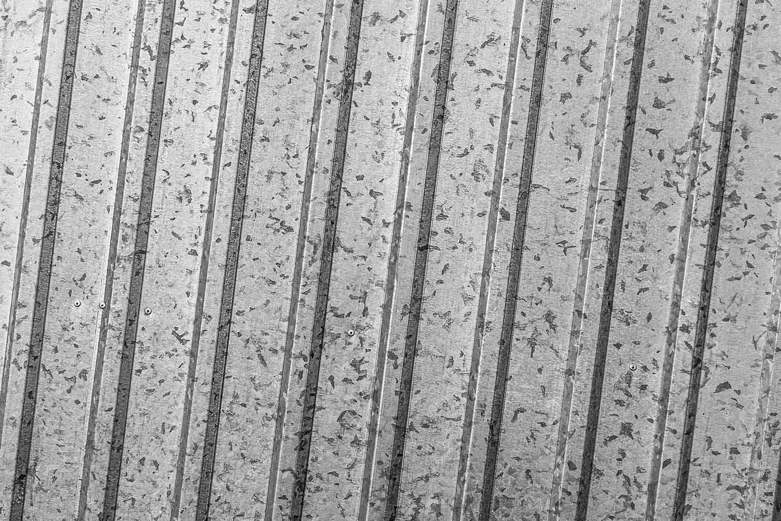 Close-up view of a galvanized metal surface showing spangle patterns and vertical ridges, illustrating coating texture relevant to adhesion evaluation.