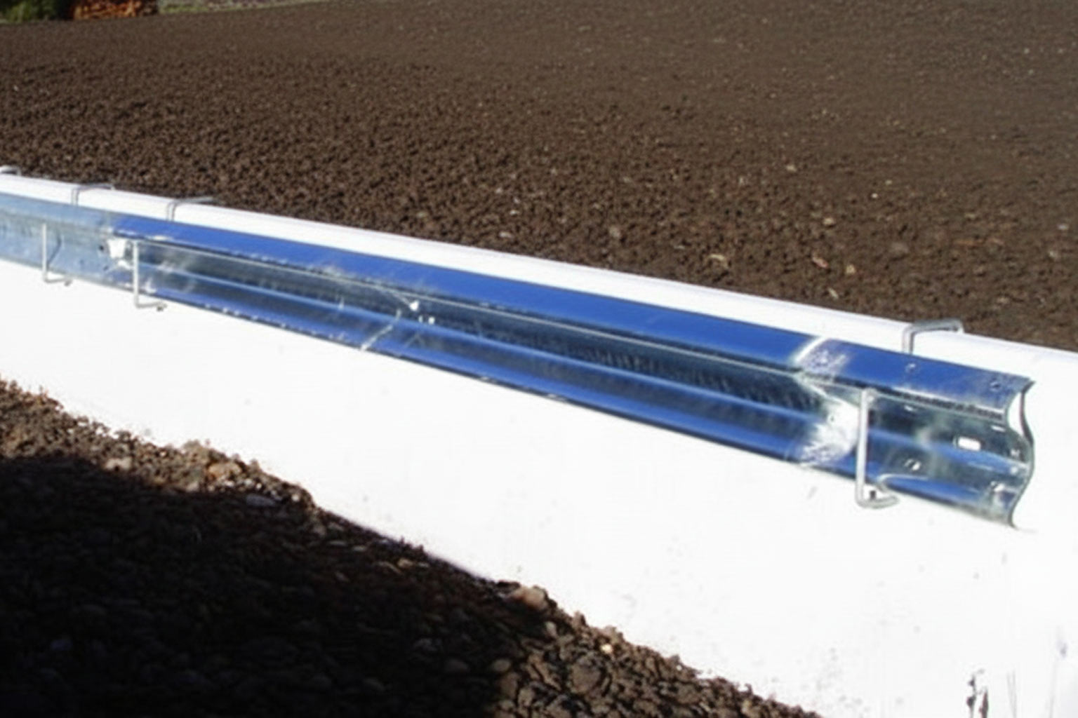 Galvanized guardrail section mounted outdoors, showing early stages of surface staining from environmental exposure.