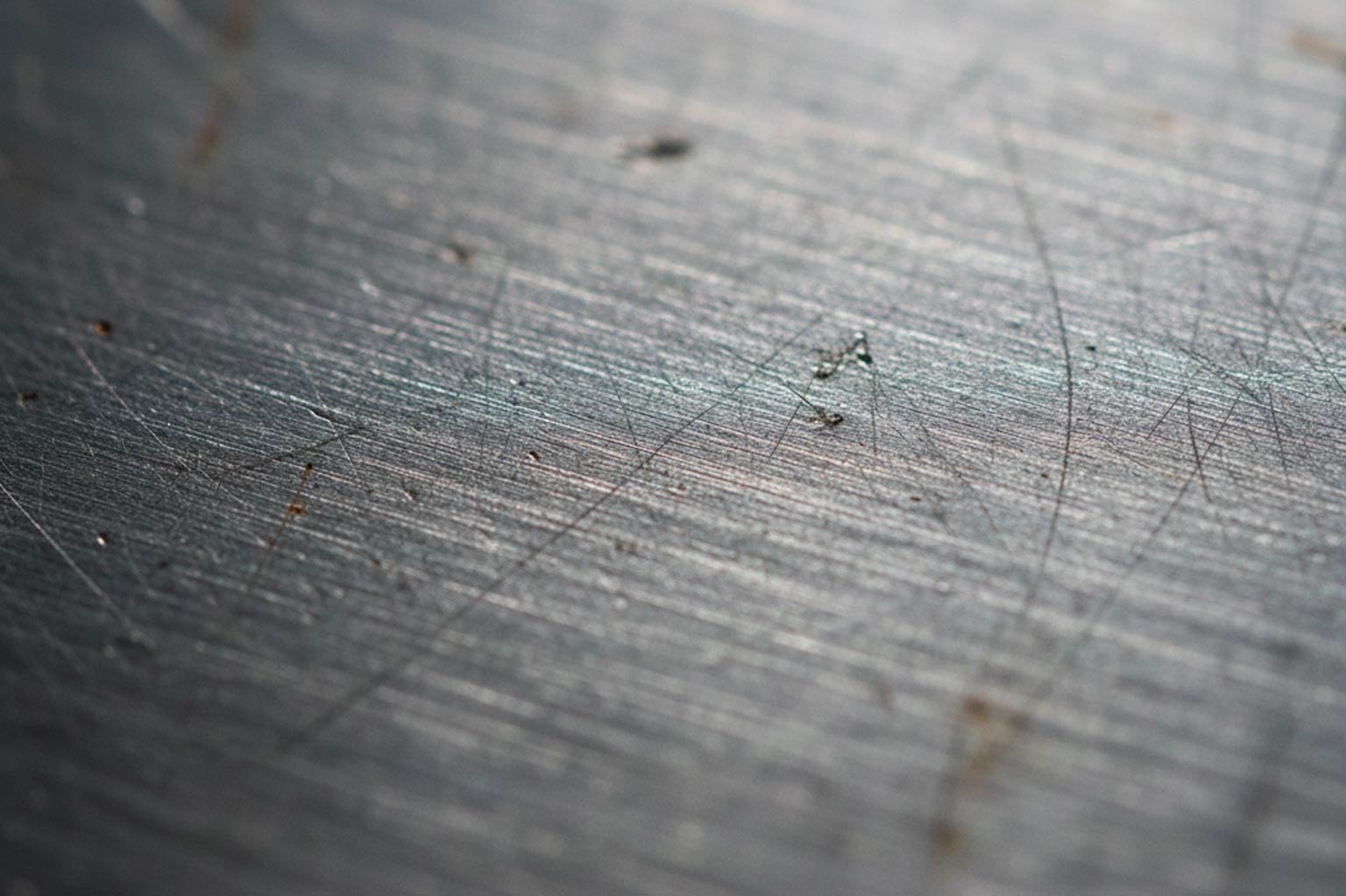 Macro close-up of a steel surface showing fine machining lines, scratches, and small imperfections that can affect galvanized coating appearance.