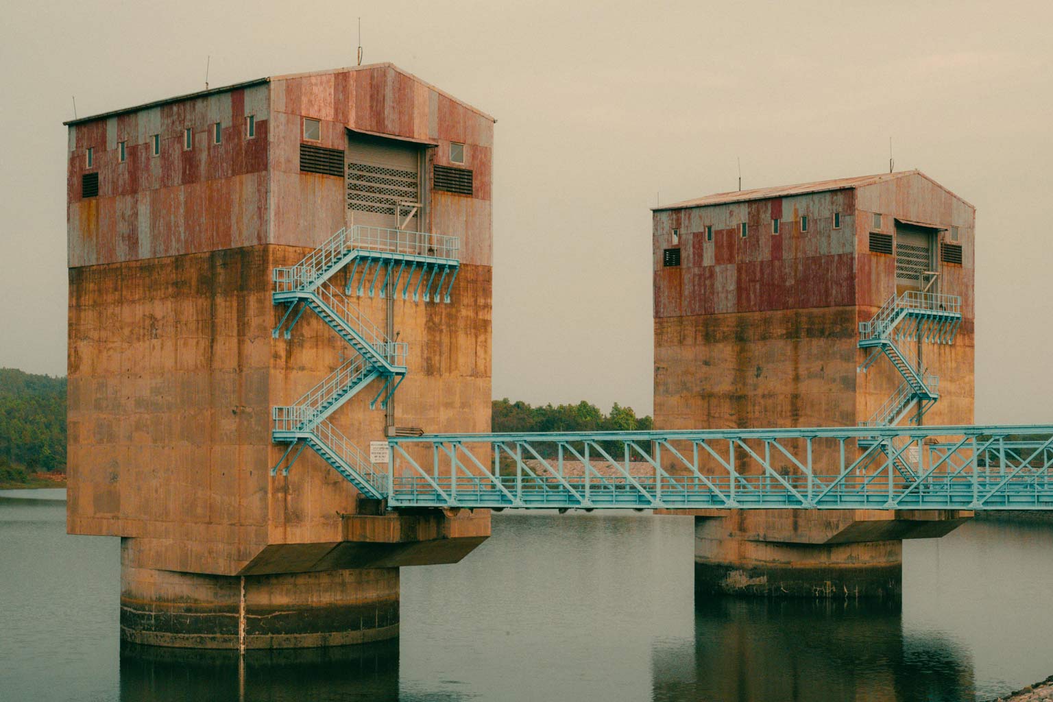 Two large water-intake towers connected by light-blue steel walkways above a reservoir, illustrating galvanized structures subject to NSF 61 potable water certification.