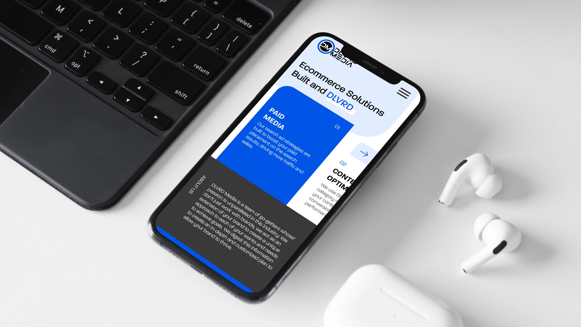 DLVRD Media homepage displayed on a smartphone beside a laptop and AirPods, highlighting mobile-friendly design