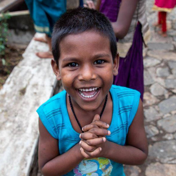 A young child clasps their hands and smiles