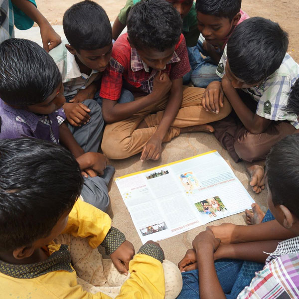 Children reading a Goodwill Childrens Home newsletter together