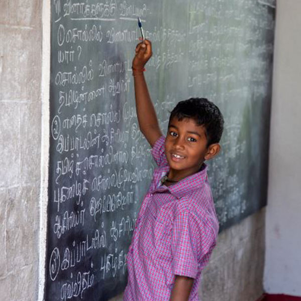 A child does a writing exercise on a chalkboard