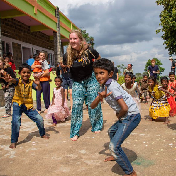 Children playing outside with a volunteer