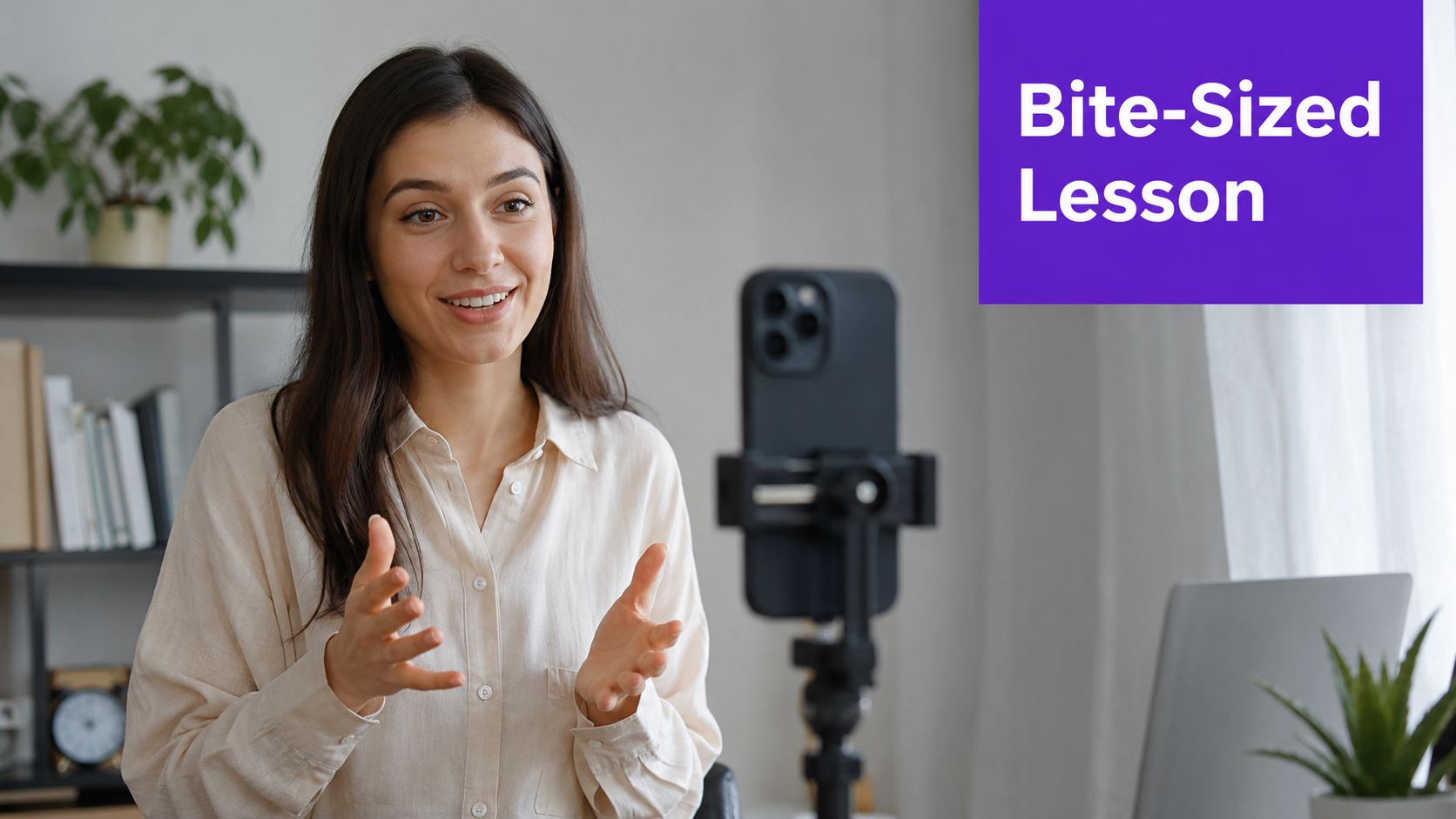 A smiling young woman recording a video lesson using a smartphone on a tripod at home.