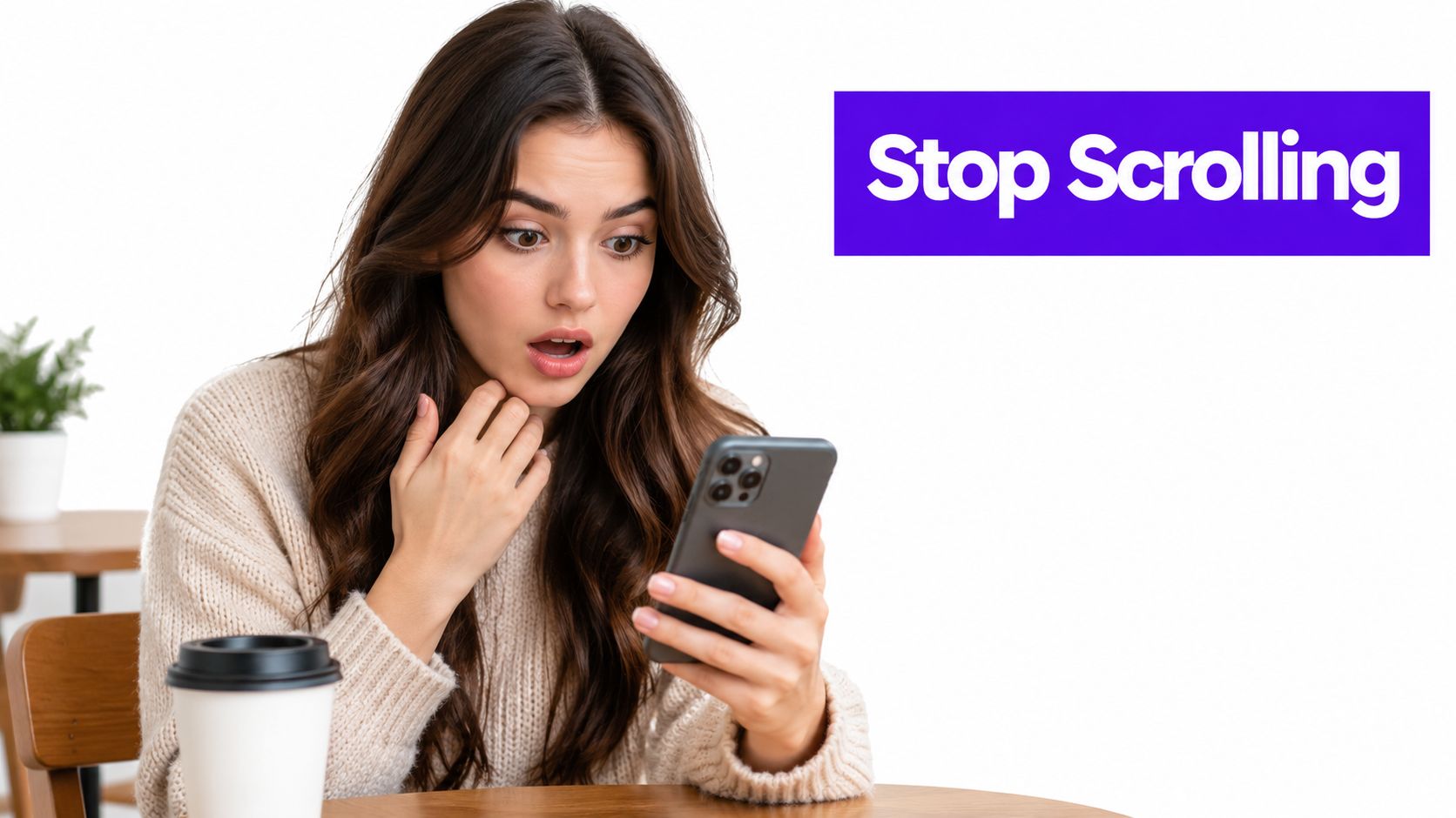 A shocked young woman looking at her smartphone while sitting with a coffee at a table.