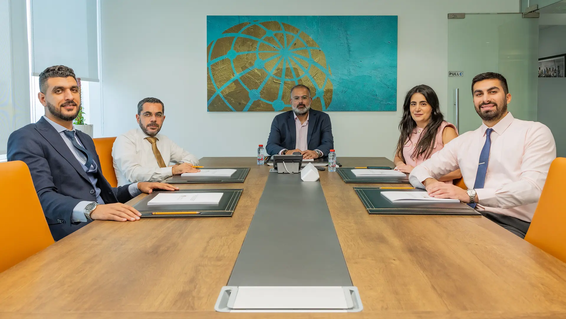 Team of lawyers from Kayrouz & Associates seated at a conference table in a modern meeting room.