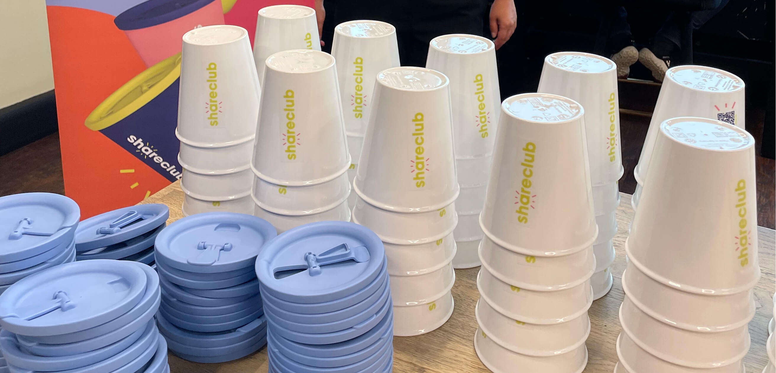 Stacks of Shareclub cups are on the table.