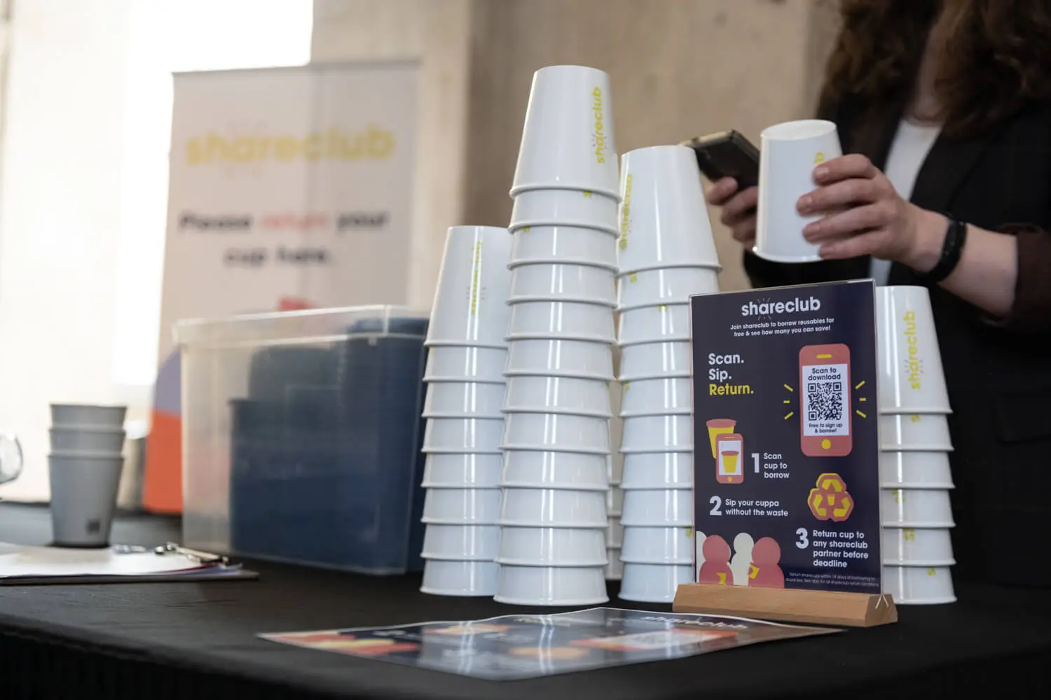 Stacks of Shareclub cups are on the table.