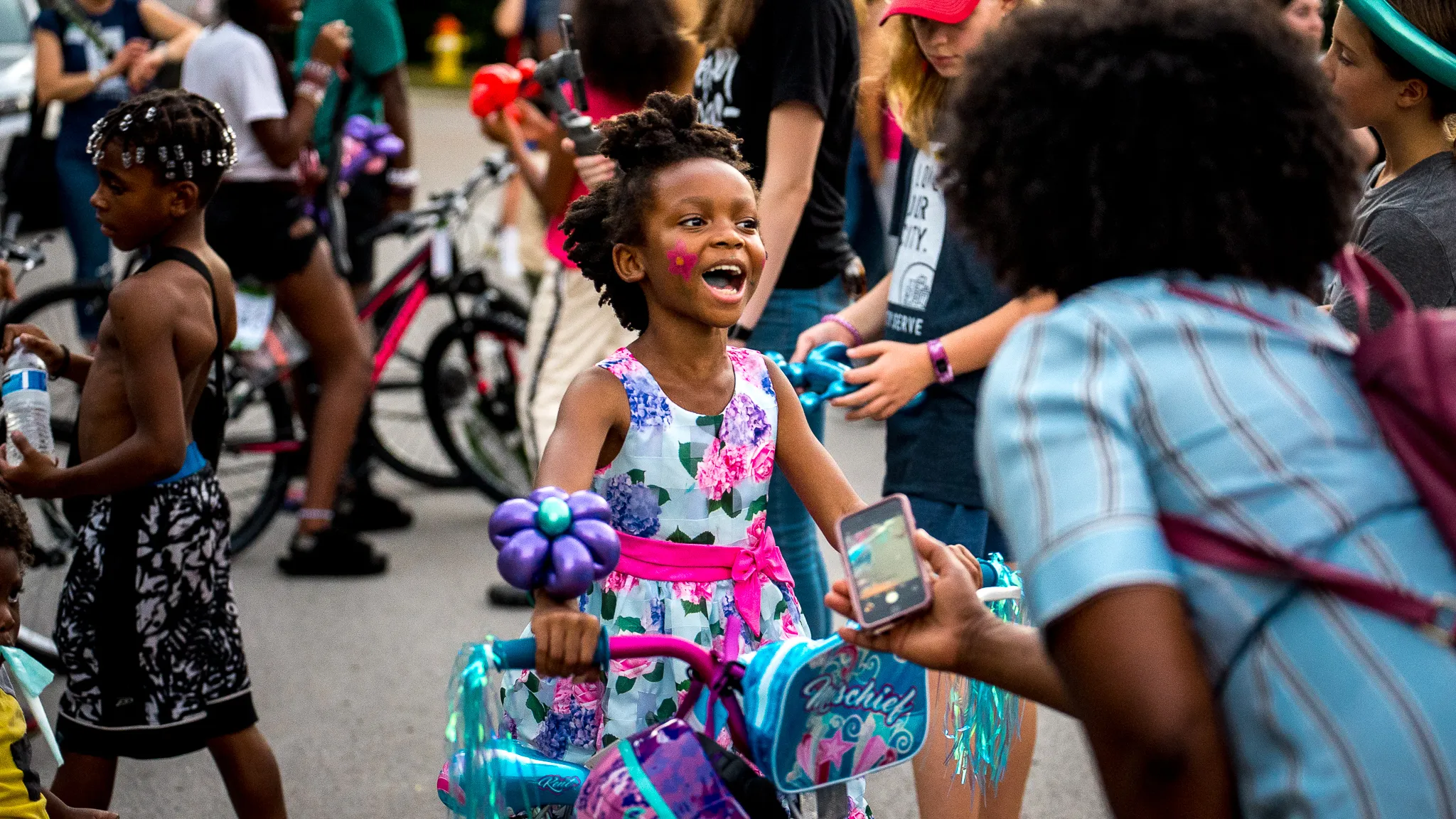 A little girl riding a bike in a parade.