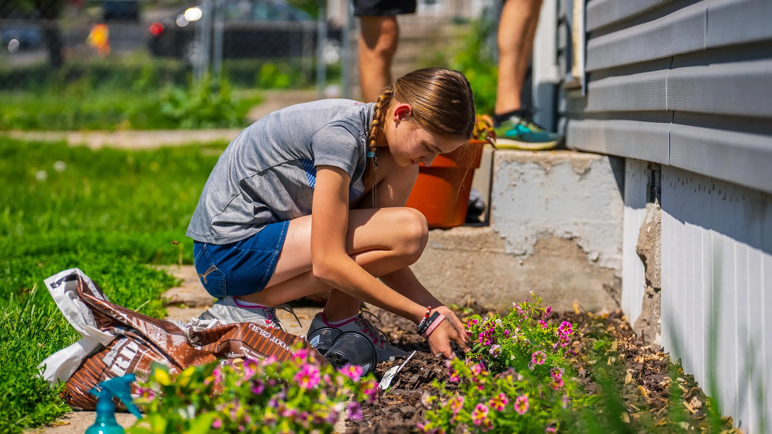 A woman kneeling down to plant some flowers.