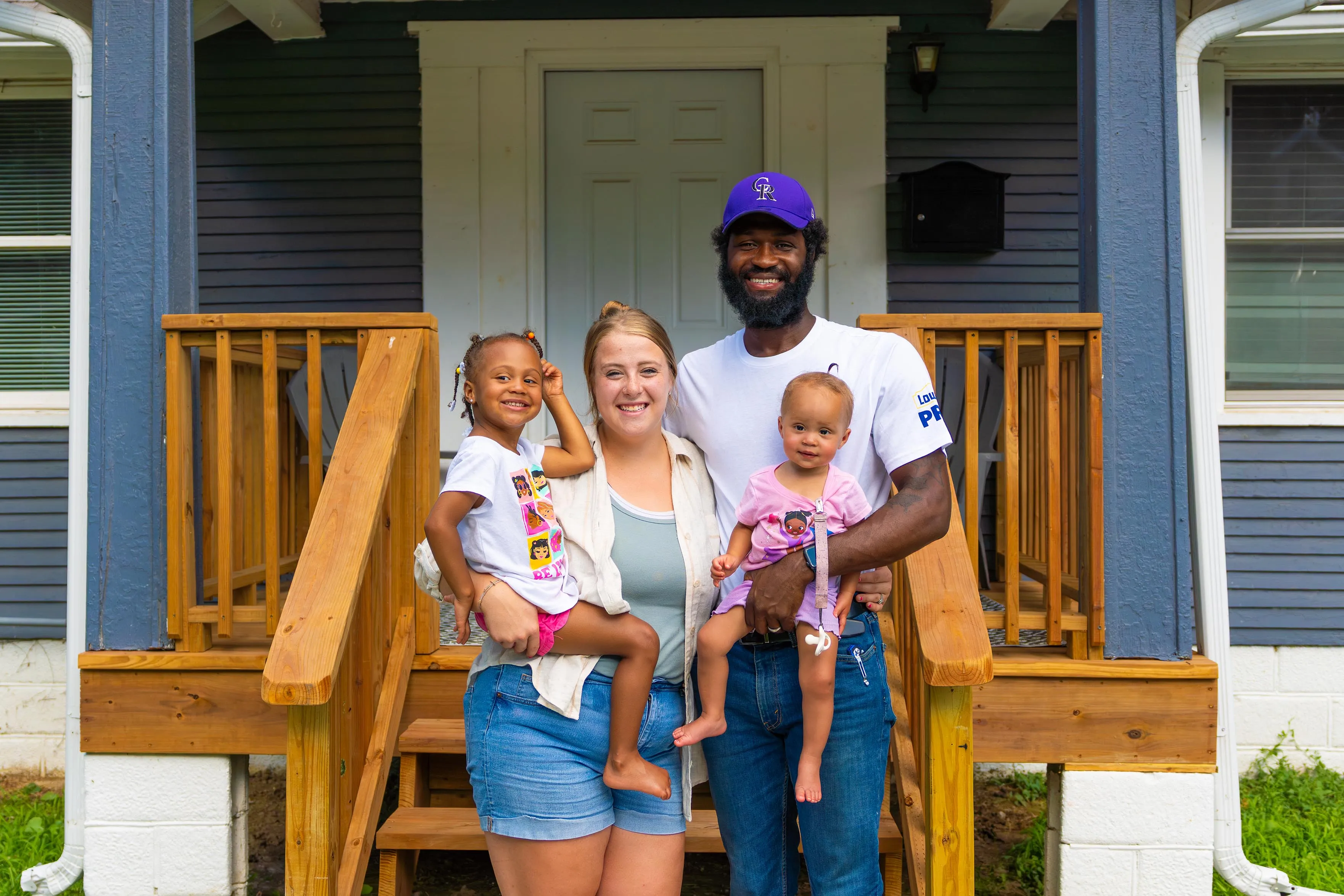 A man, woman and two children standing in front of a house.