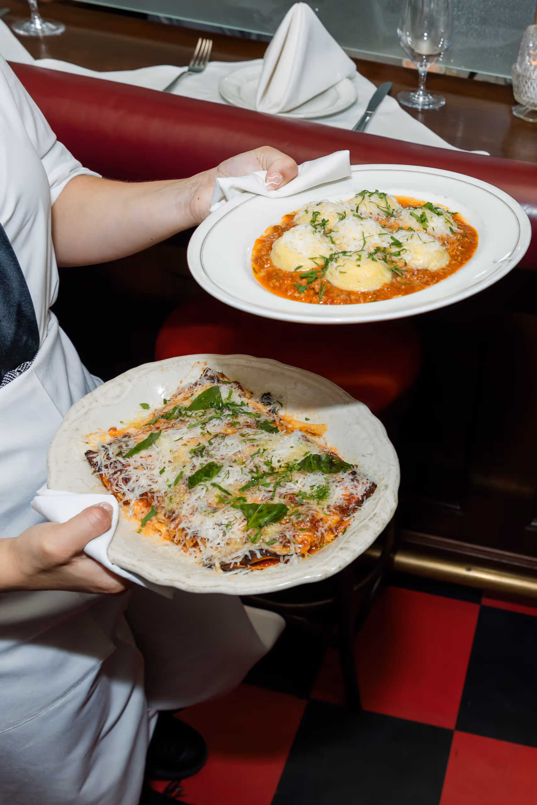 Server carrying two plates topped with grated cheese.