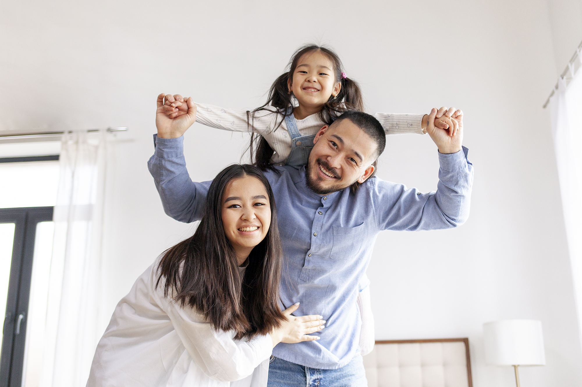 happy-asian-family-with-little-daughter-stand-home-rejoice-mom-dad-hold-child