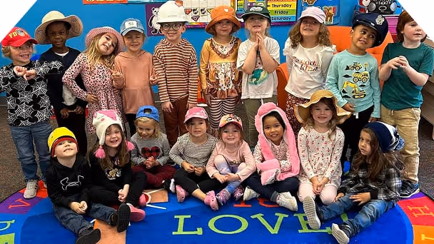 a group of preschoolers posing for a class photo while wearing hats