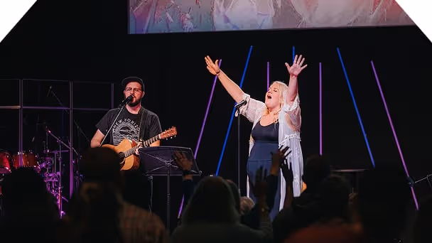 A woman raising her hands in praise while singing