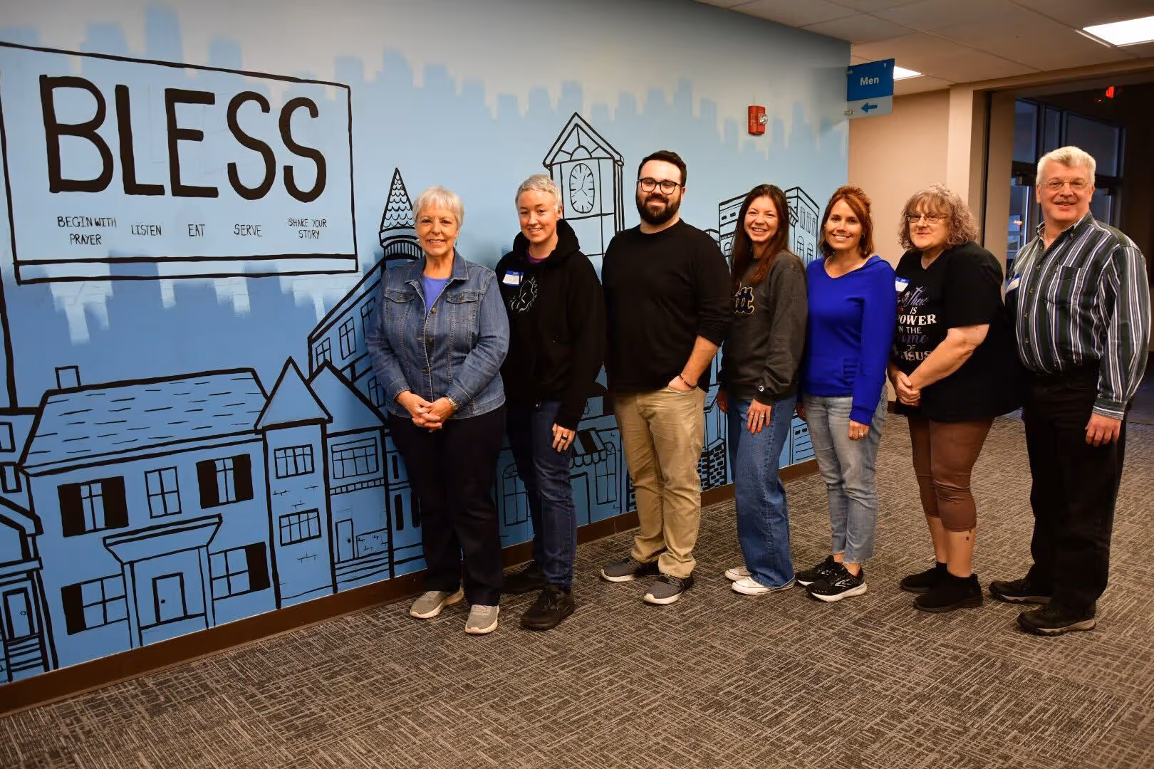 Seven members of a recent group posing together 