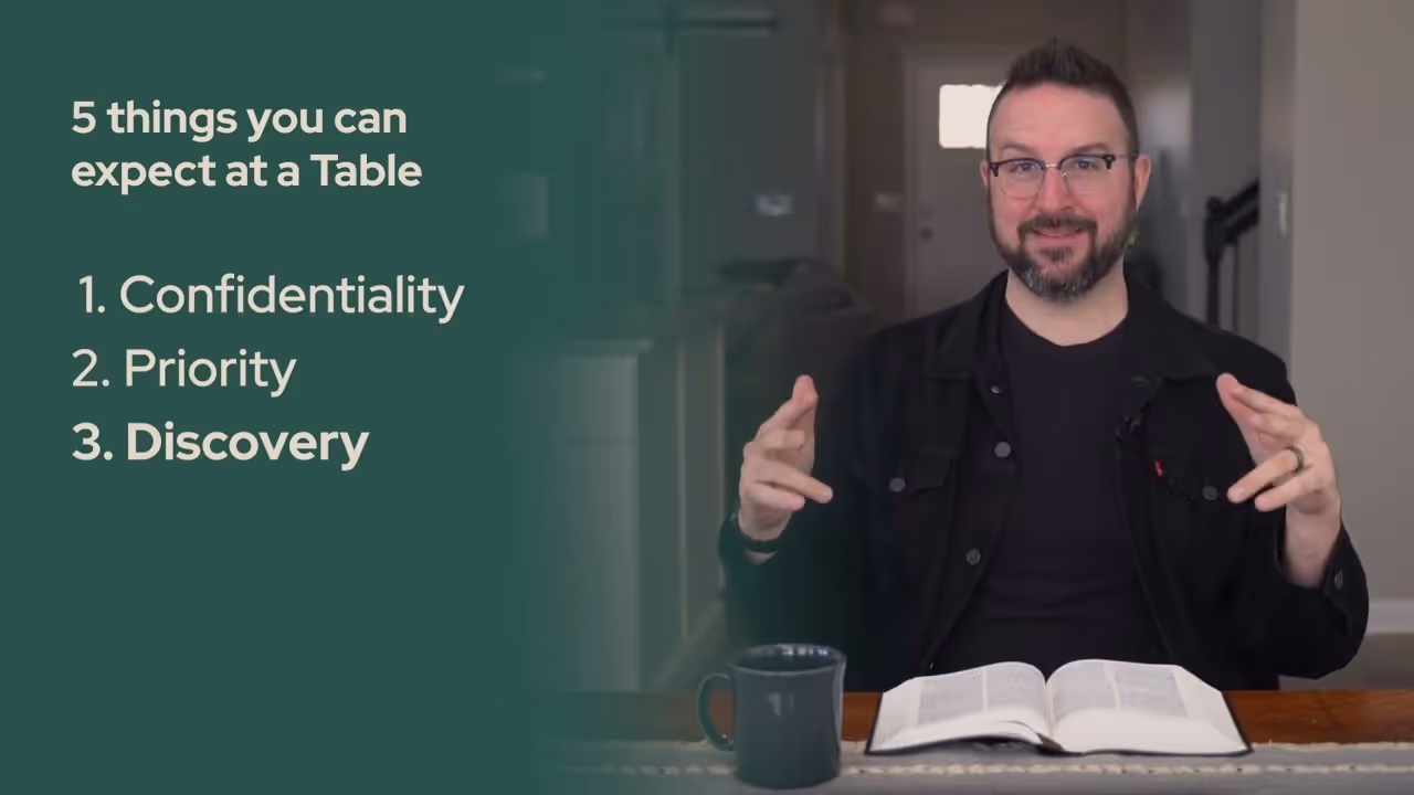 a man sitting at a table with a book and a mug