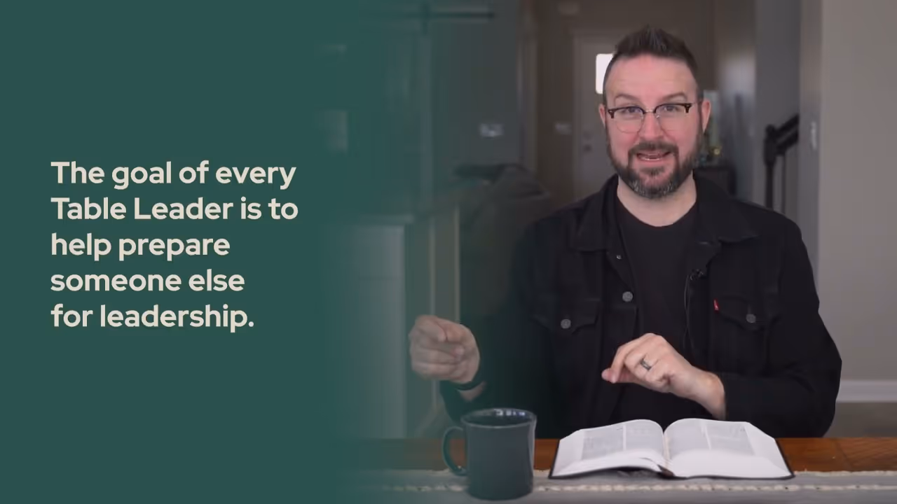 a man sitting at a table with a book and a mug
