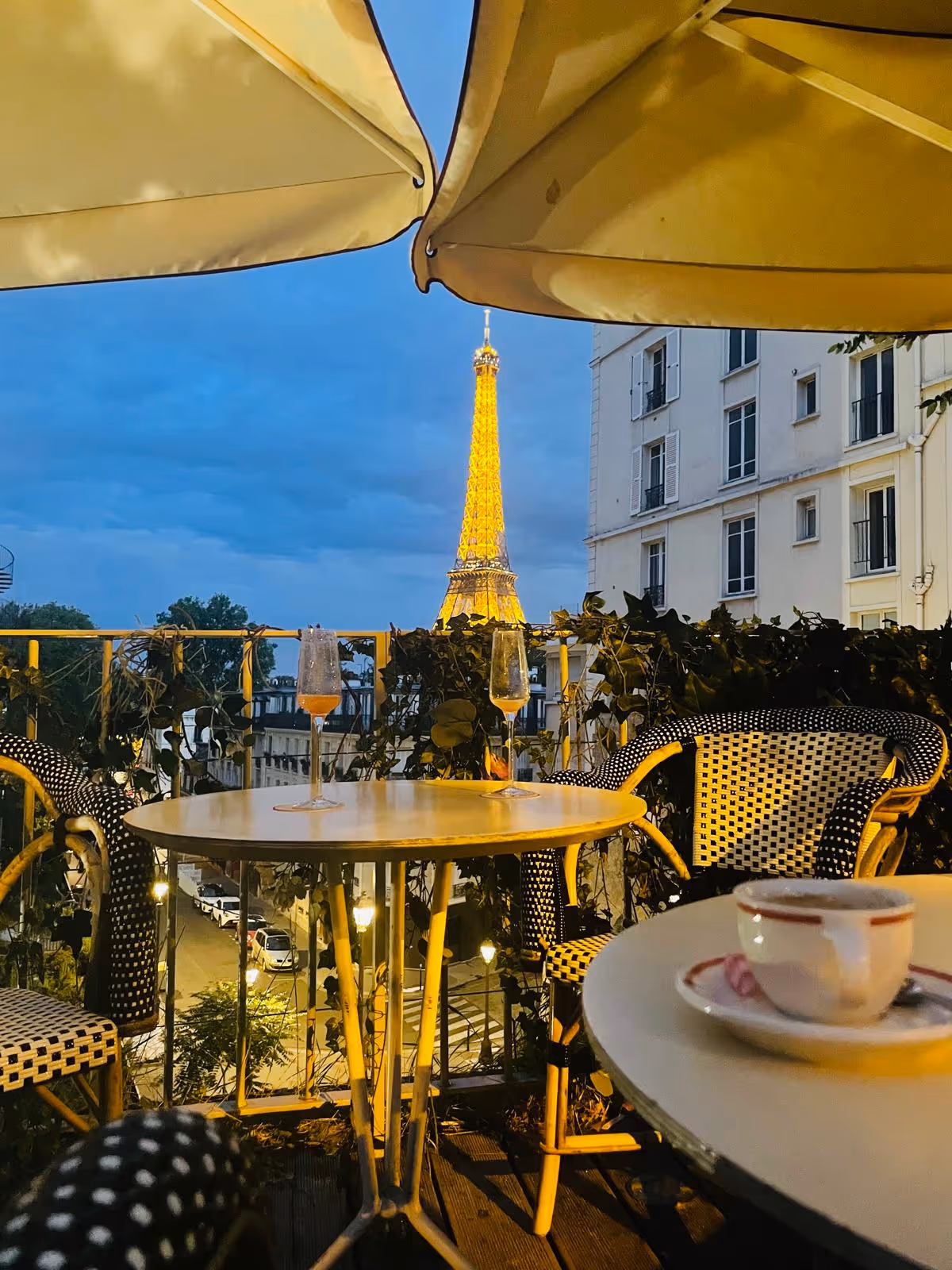 Terrasse parisienne avec vue sur la Tour Eiffel illuminée au crépuscule