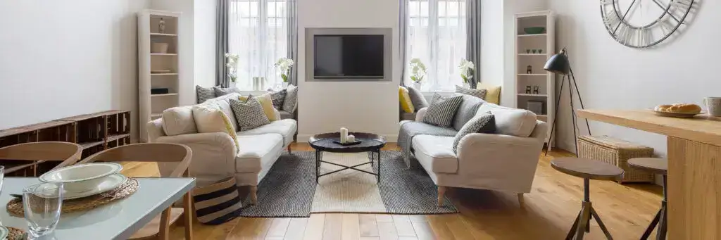 Modern living room with gray sofas, yellow accents, and large wall clock