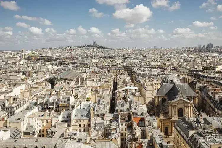 Vue panoramique sur Paris, mettant en avant les toits haussmanniens et la basilique du Sacré-Cœur.