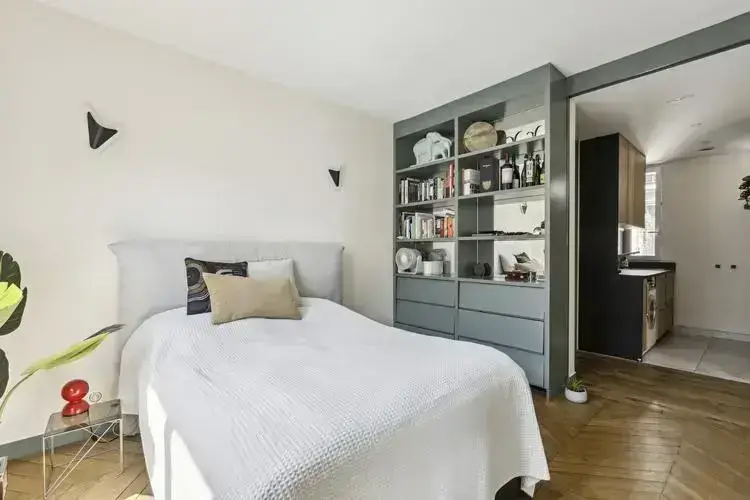Chambre moderne d'un appartement de luxe à Paris, avec parquet élégant et rangements intégrés.