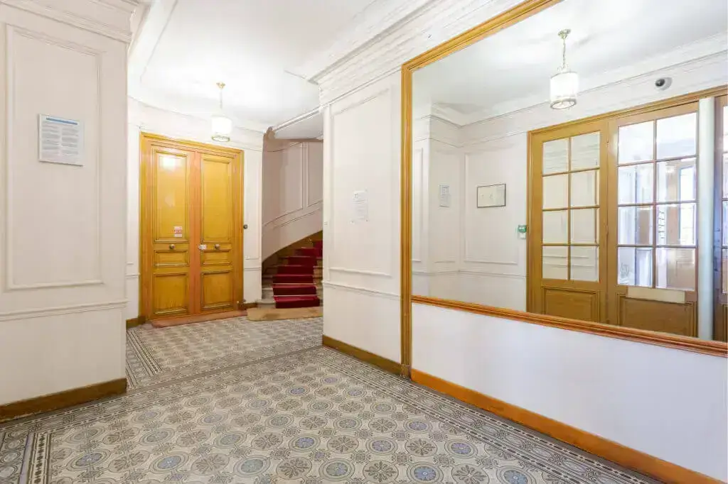 Elegant hallway with yellow doors, ornate floor, and staircase leading up