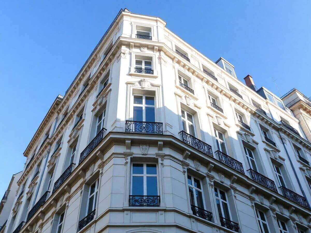 White Parisian apartment building with ornate black balcony railings