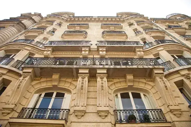Façade élégante d'un appartement de luxe à Paris, ornée de balcons avec fer forgé et sculptures détaillées.
