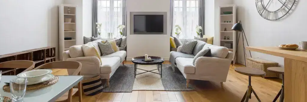 Modern living room with gray sofas, yellow accents, and large wall clock