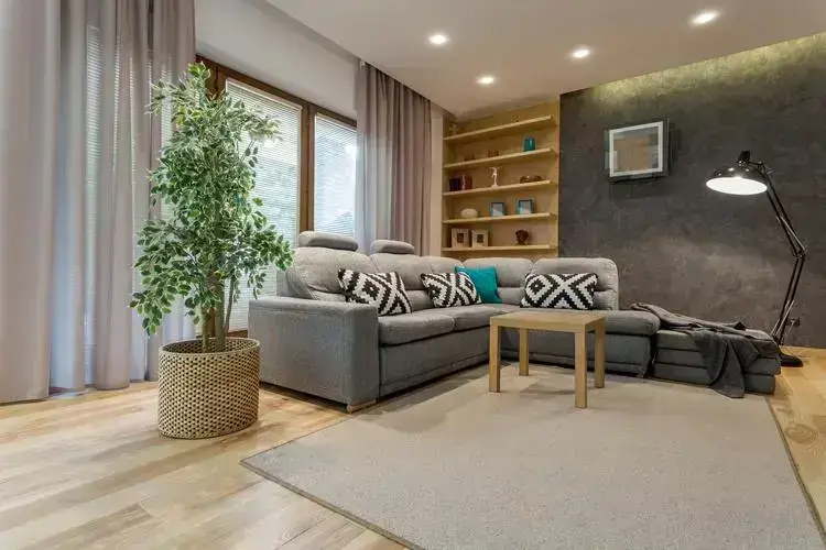 Salon moderne d'un appartement de luxe à Paris, avec éclairage chaleureux, plantes vertes et murs texturés.