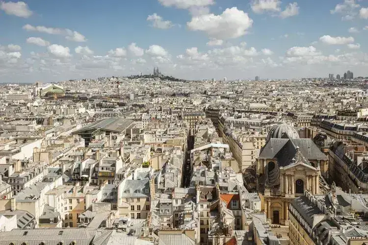 Vue panoramique sur Paris, mettant en avant les toits haussmanniens et la basilique du Sacré-Cœur.