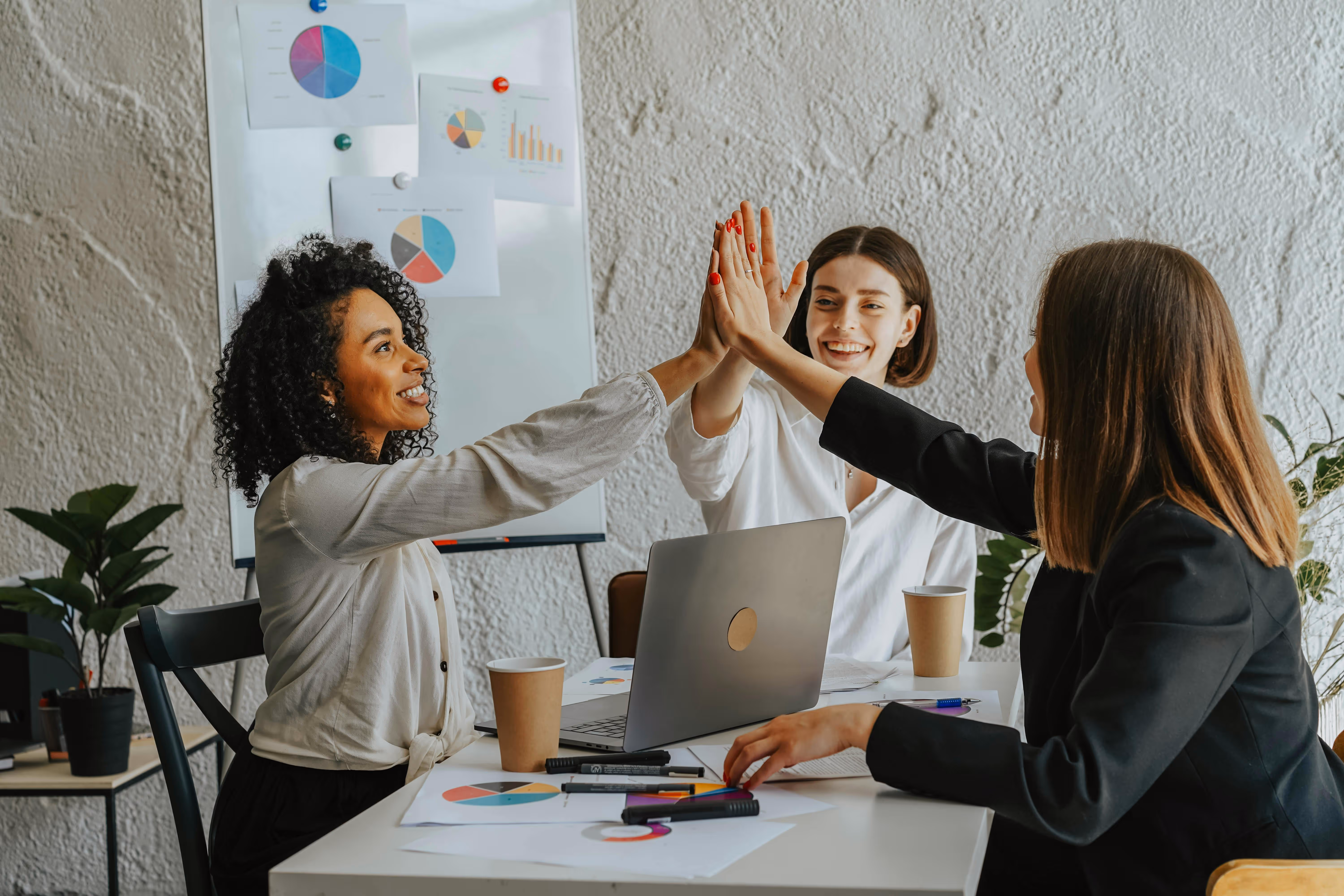 A group of professional women celebrating their efficient business process improvement.