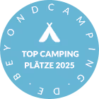 Rundes, blaues Abzeichen mit weißem Text 'Top Camping Plätze 2025' und Zelt-Symbol in der Mitte, umgeben vom Text 'beyondcamping.de'.