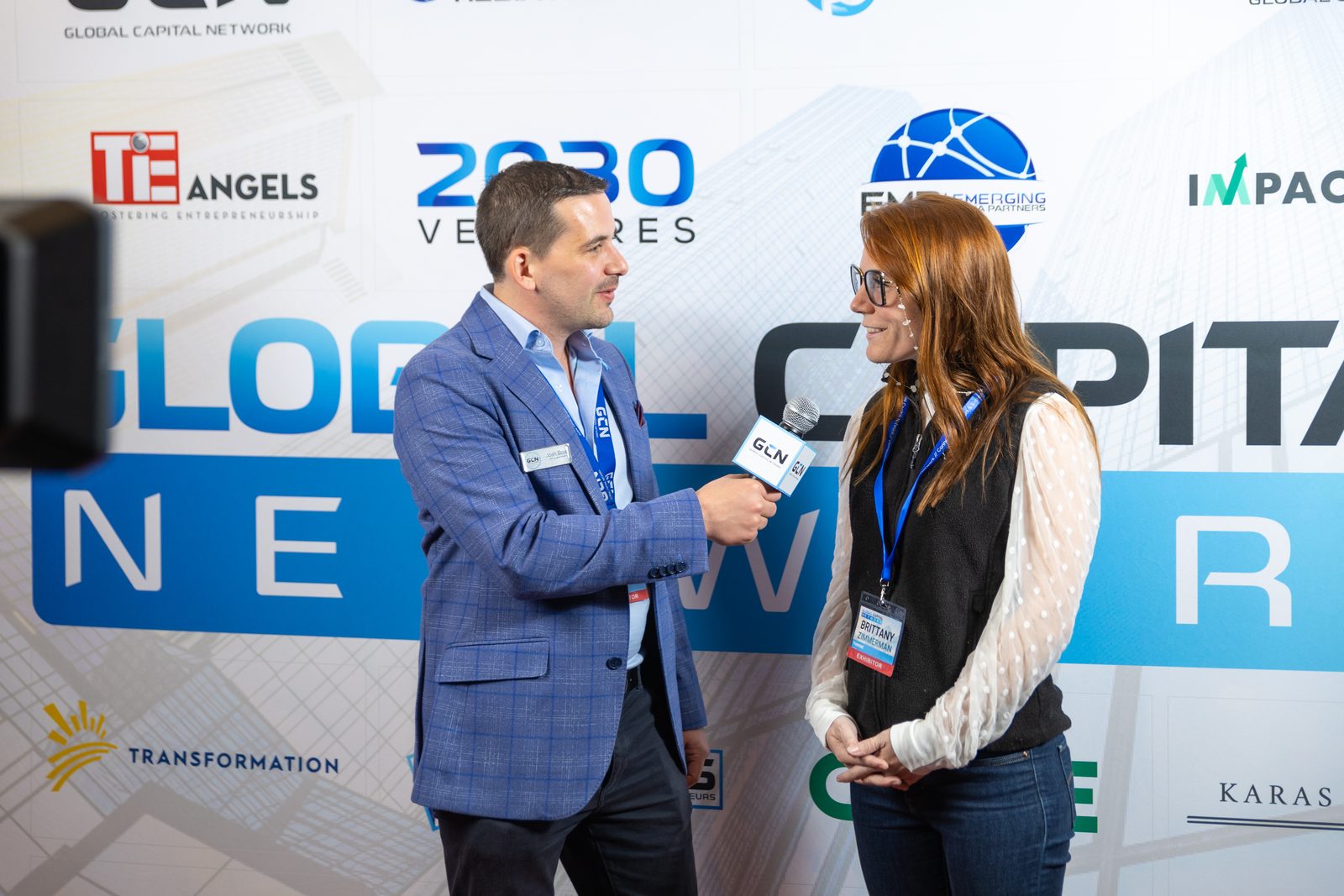 Josh Bois interviewing an exhibitor at the GCN press wall