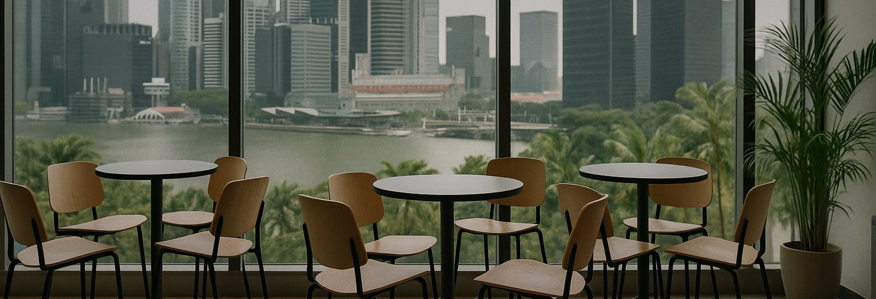 several empty chairs pulled together around small high tables, ready for founders to meet, with Singapore towers and tro