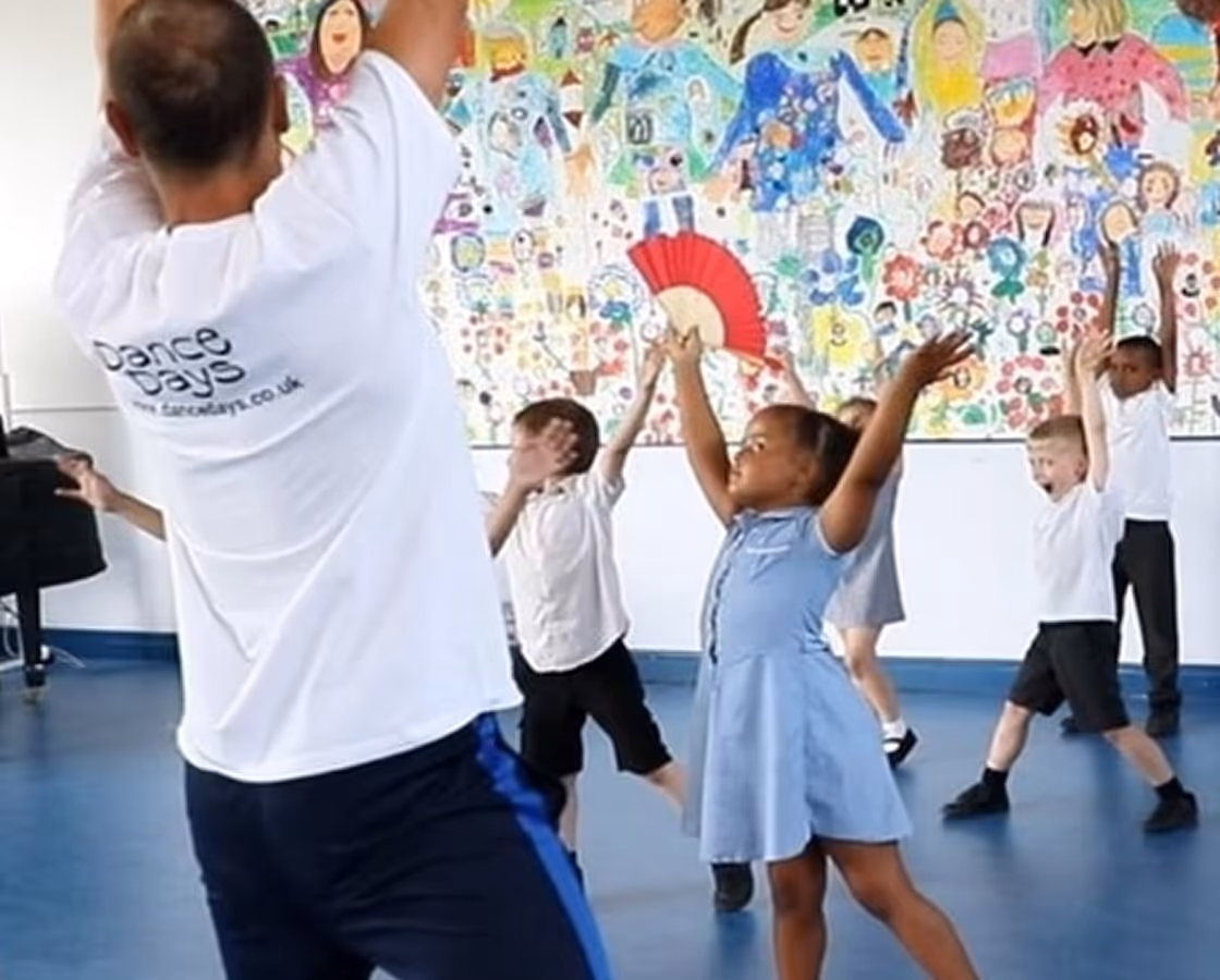 Excited school children dancing in a workshop, used on the contact page to reflect the joyful experience Dance Days offers.