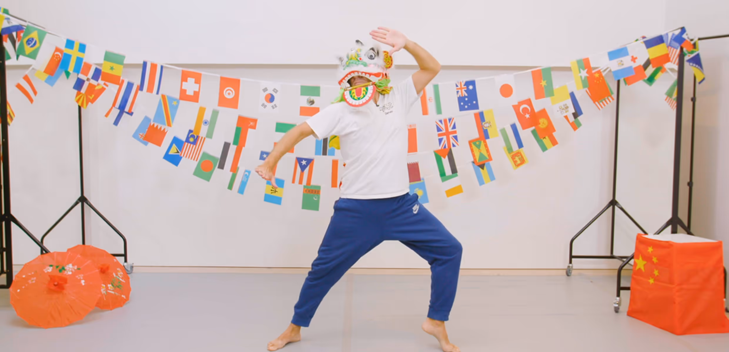 Instructor guiding students through a traditional Chinese dance workshop in a school setting, demonstrating cultural movements with vibrant props.
