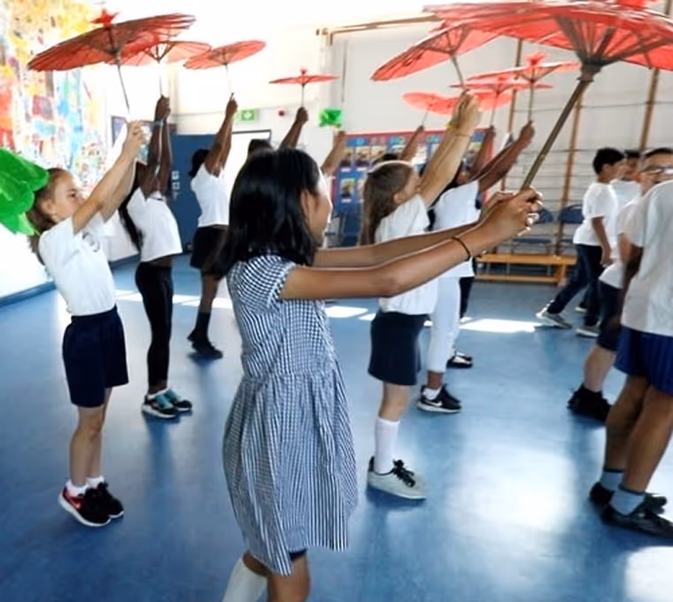 Kids dancing in a school hall as part of a creative workshop, expressing themselves through movement.