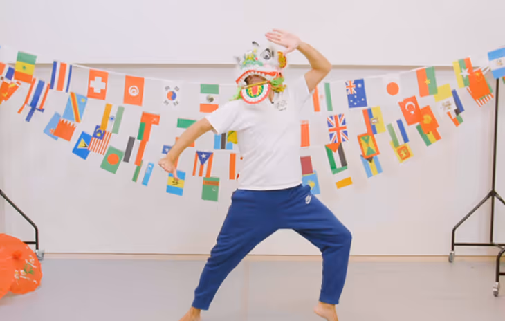 Instructor guiding students through a traditional Chinese dance workshop in a school setting, demonstrating cultural movements with vibrant props.
