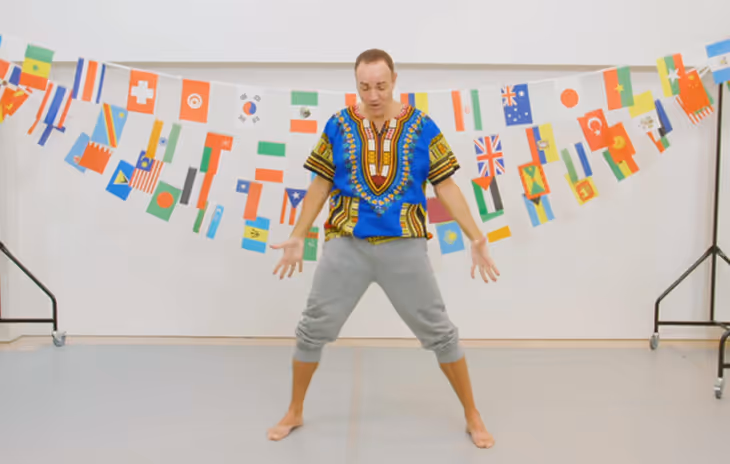 Instructor guiding students through energetic African dance routines, using traditional rhythms and full-body movements in a school workshop.

