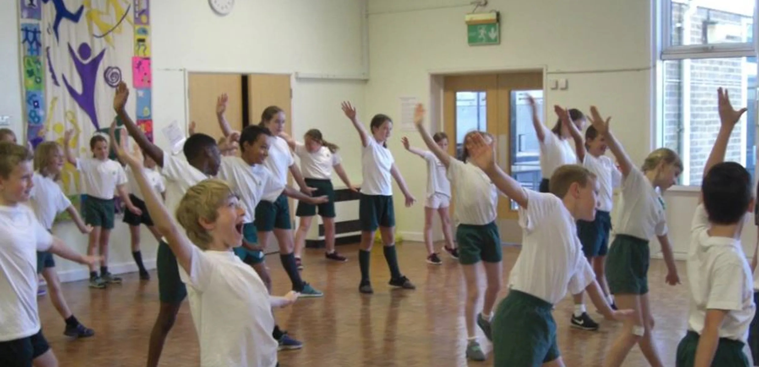 A teacher guiding children through dance steps, helping them choose and explore movements in a vibrant classroom environment.