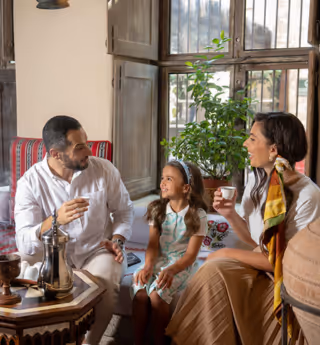 Family sitting together in a cozy, traditional-style room, enjoying tea and conversation.