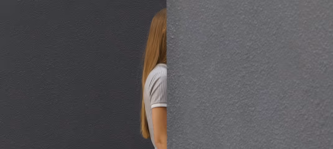 Person partially hidden behind a gray wall.