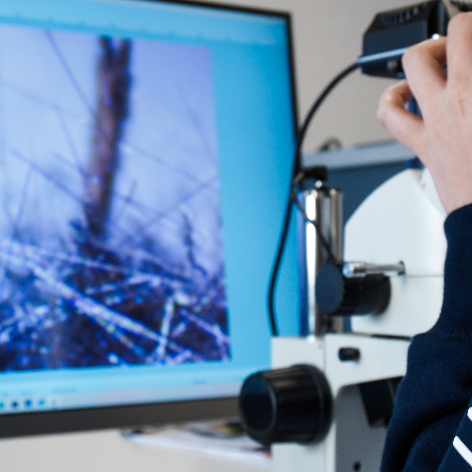 Person examining recycled carbon fiber material under a microscope