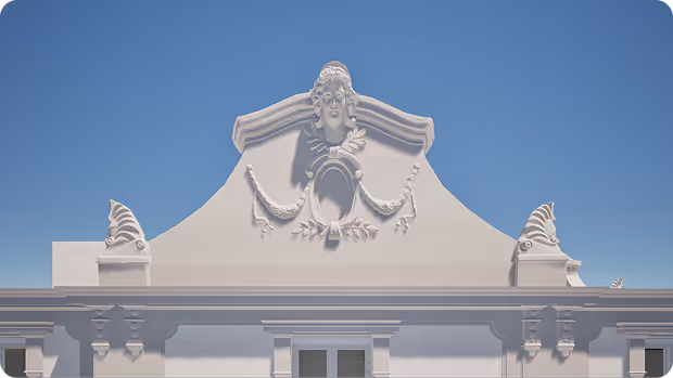 Ornate white building facade with sculpted face and decorative elements under clear blue sky.